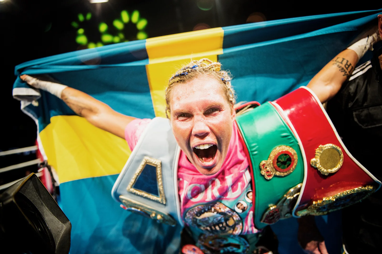 Mikaela Laurén firar i boxningsringen med mästarbälten och en svensk flagga