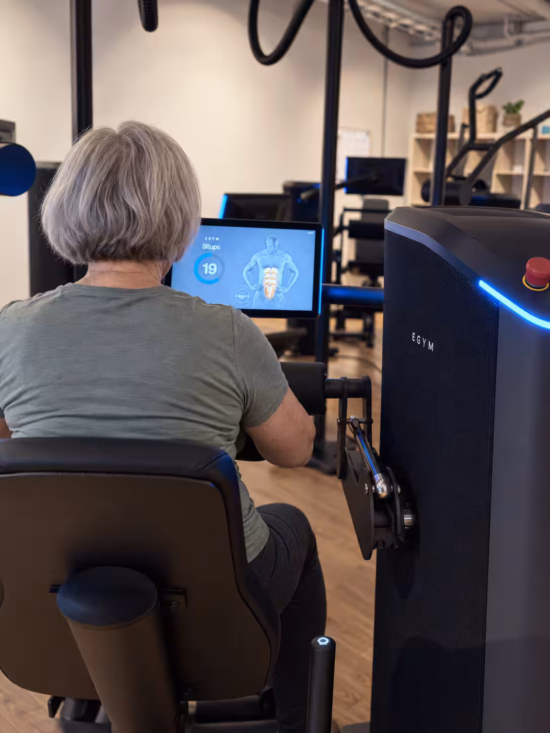 Äldre kvinna sedd bakifrån vid en EGYM-maskin
